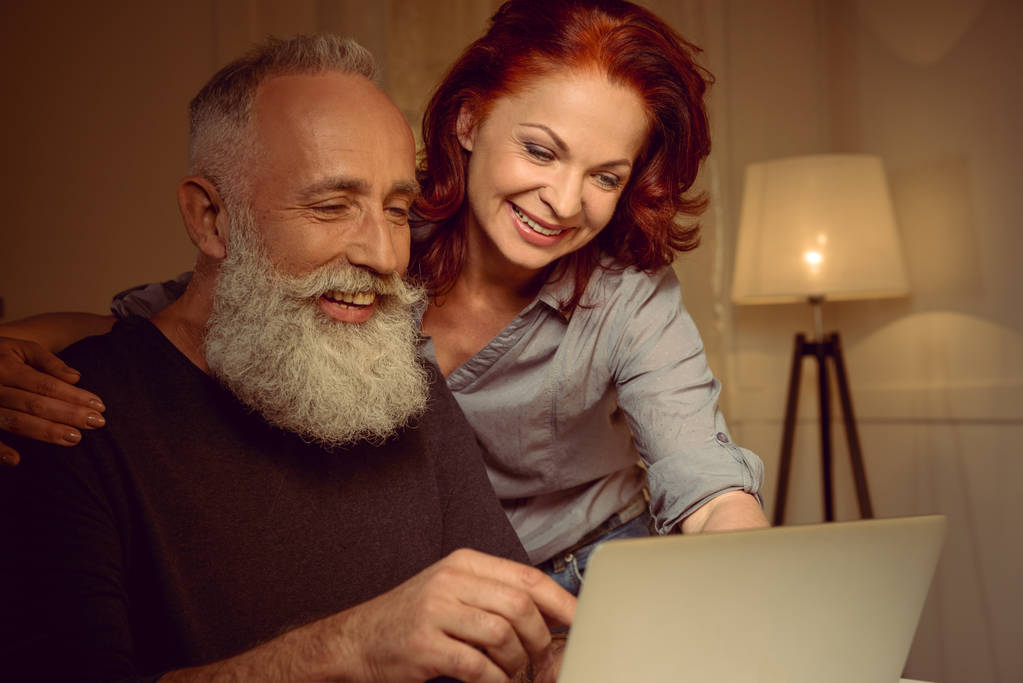 Среднего возраста пара глядя на ноутбук
 - Фото, изображение
