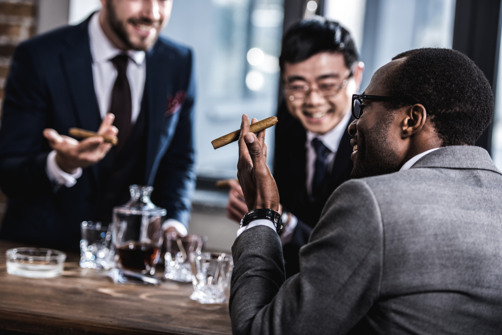 multiculturele business team tijd doorbrengen, sigaren roken en drinken van whisky  - Foto, afbeelding