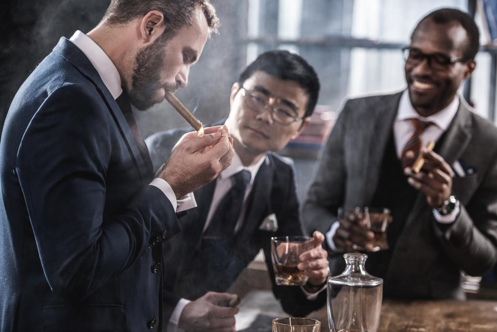Команда мультикультурного бізнесу витрачає час, курить сигари та п'є віскі
 - Фото, зображення