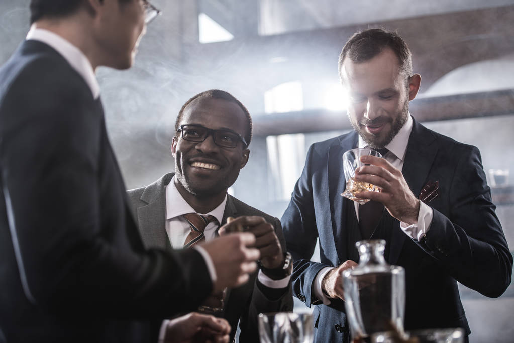 Wielonarodowa Grupa biznesmenów spędzać czas razem picie whisky i palenia, wielokulturowym działalności zespołu - Zdjęcie, obraz