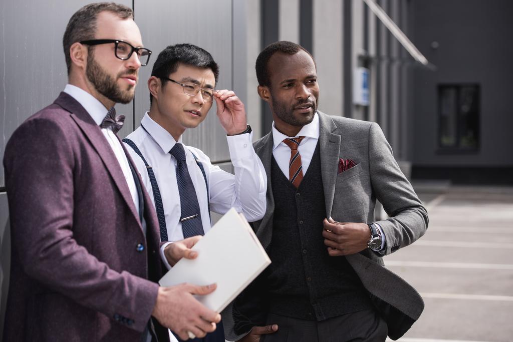 retrato da equipe de negócios multicultural confiante que está perto do escritório e olhando para o lado
  - Foto, Imagem