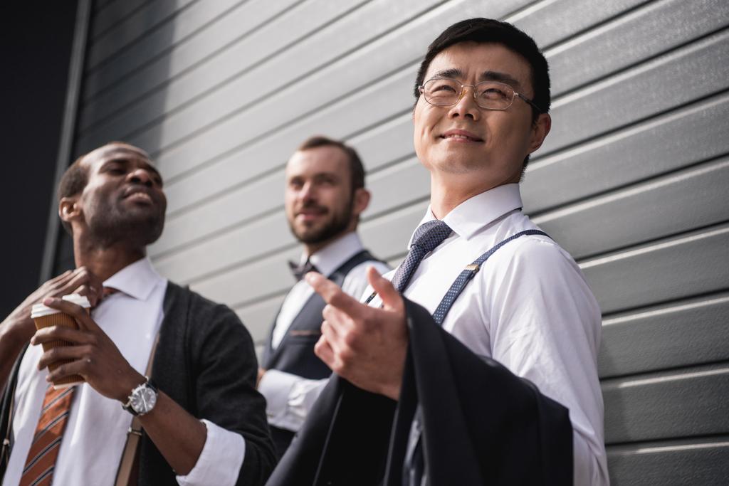 junge stilvolle multiethnische Geschäftsleute in Formalbekleidung, die draußen stehen, Besprechung des Geschäftsteams - Foto, Bild