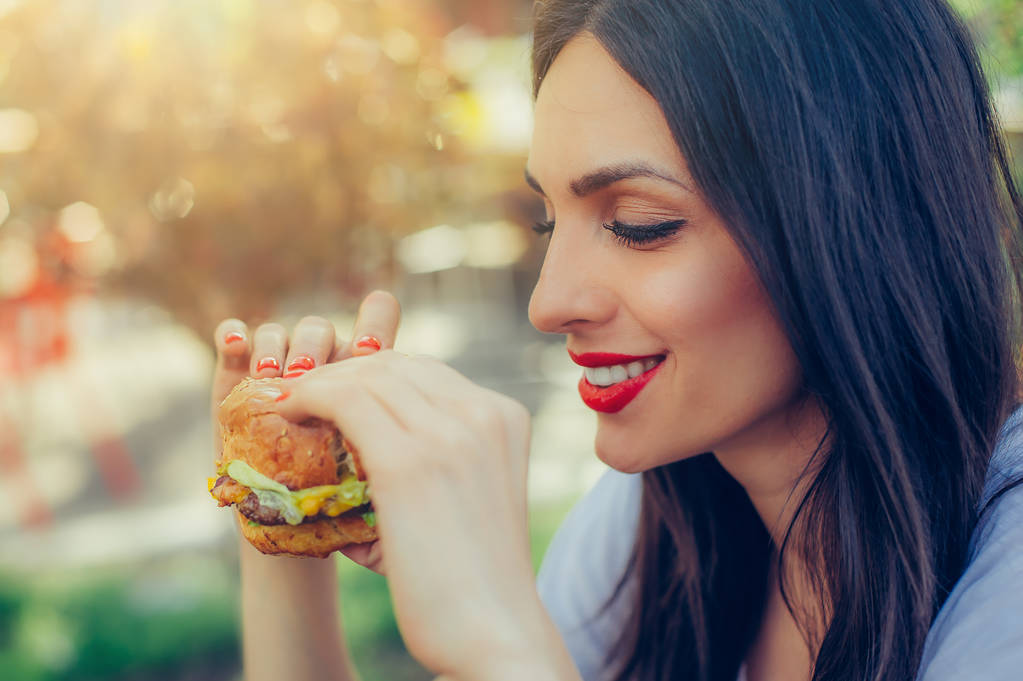 Ευτυχισμένη γυναίκα τρώνε μπιφτέκι νόστιμο γρήγορο φαγητό - Φωτογραφία, εικόνα
