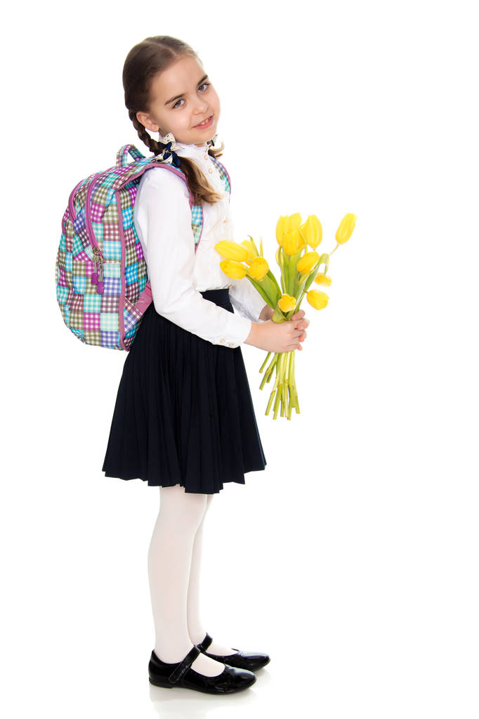 ein Schulmädchen mit einem Blumenstrauß und einem Rucksack auf dem Schoß - Foto, Bild