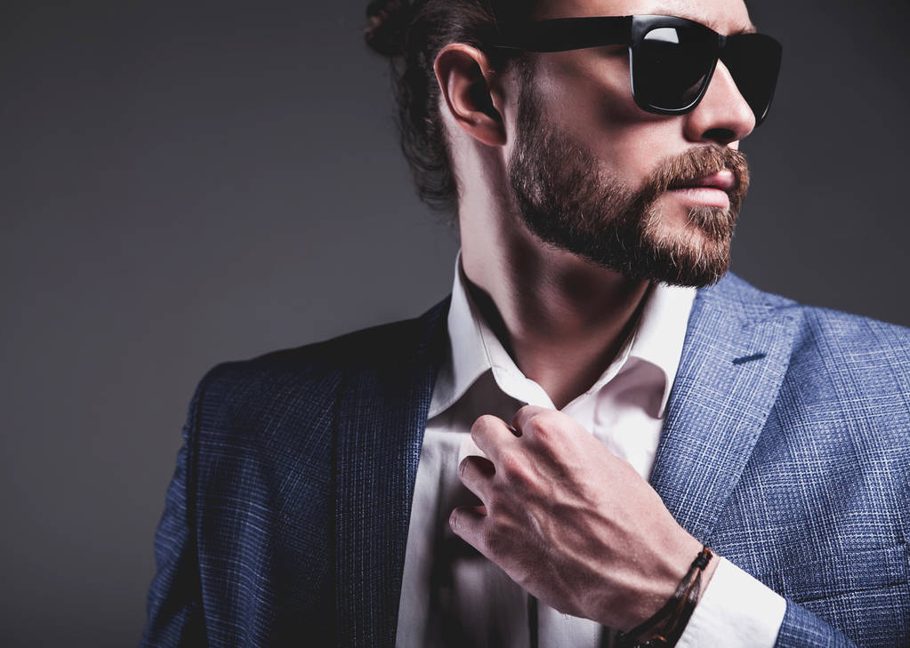 hübsche Mode stilvolles Hipster-Geschäftsmann-Modell in elegantem blauen Anzug posiert auf grauem Hintergrund - Foto, Bild