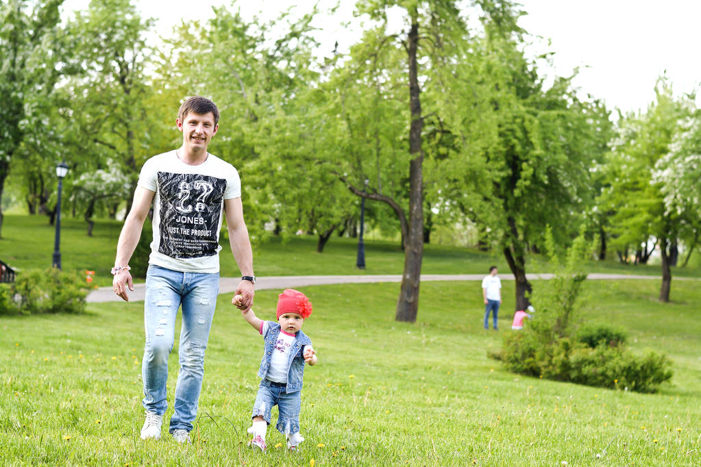 父と幼い娘が公園を歩く - 写真・画像