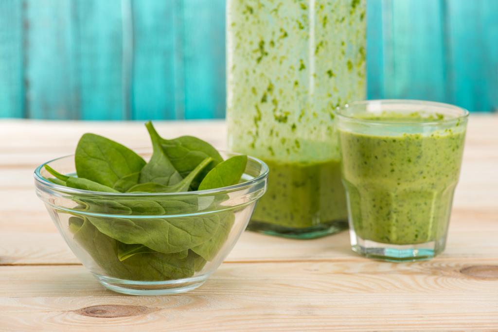 groene bladeren en smoothie in glas en fles - Foto, afbeelding