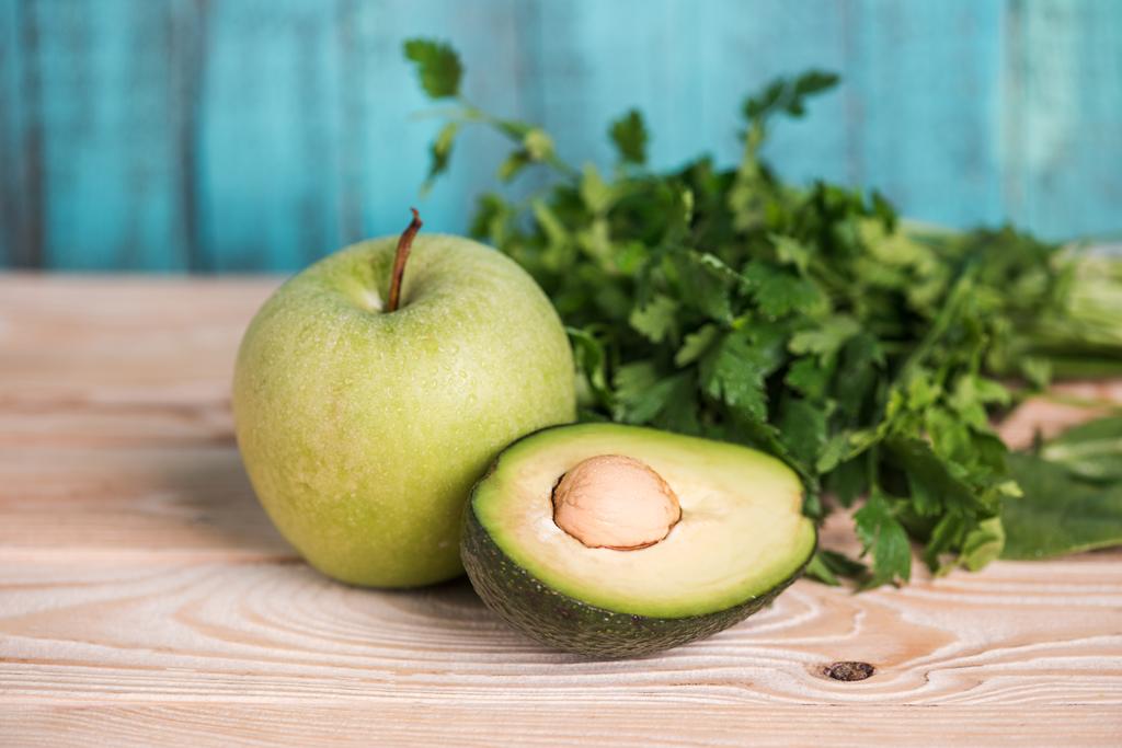 reife Avocado mit Petersilie und Apfel auf Holztisch - Foto, Bild