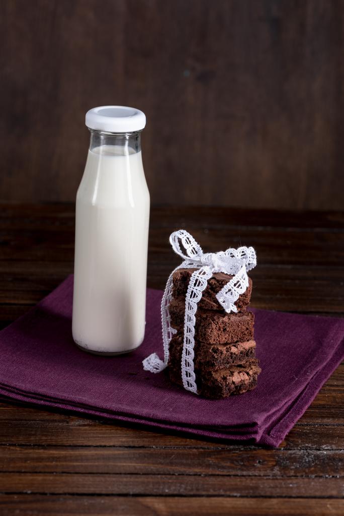 botella de leche con pasteles de brownie en la servilleta
 - Foto, imagen