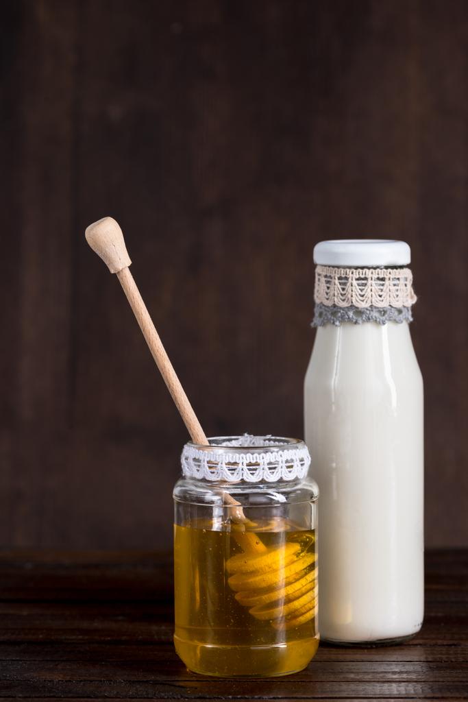 γυάλινο μπουκάλι γάλα με μέλι σε βάζο - Φωτογραφία, εικόνα