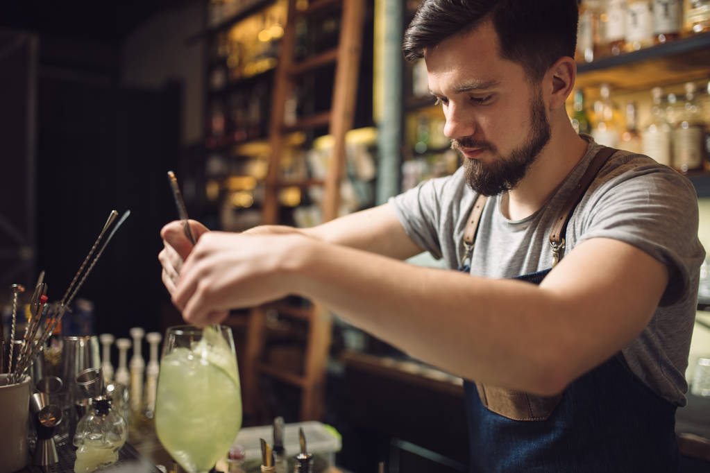 junger männlicher Barkeeper bereitet einen Alkohol-Cocktail zu - Foto, Bild