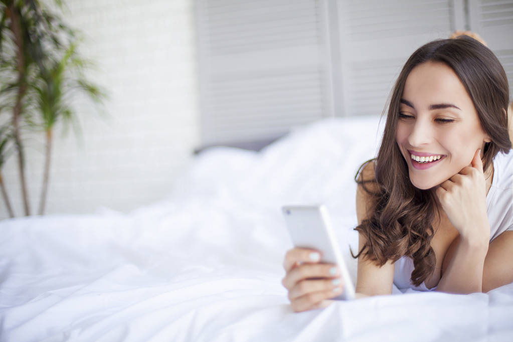 woman using mobile in bedroom - Photo, Image