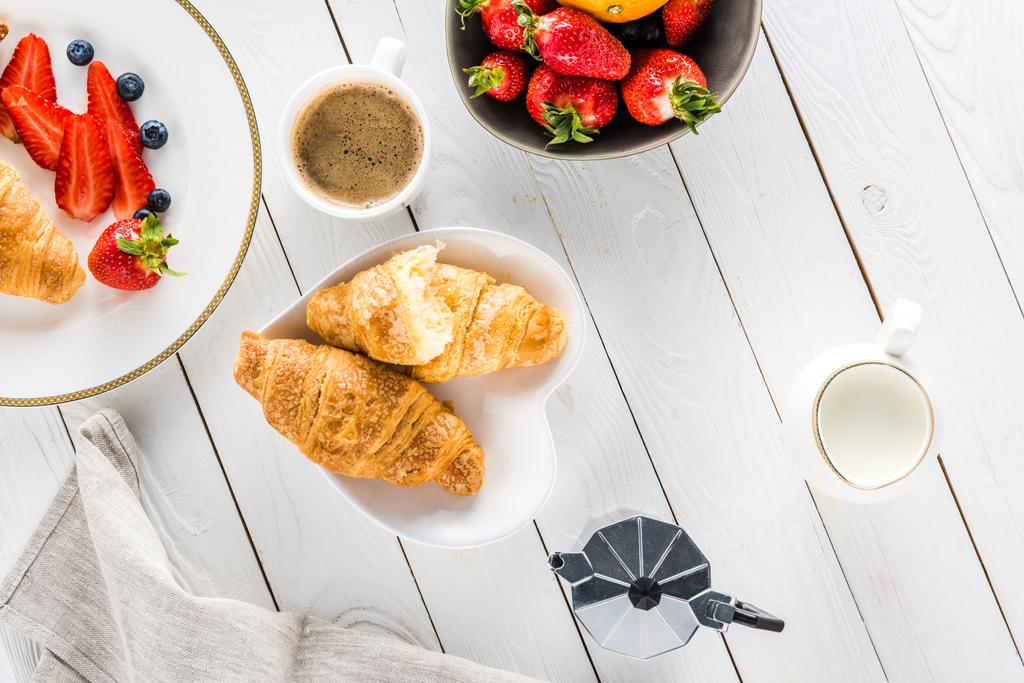 croissants with coffee and strawberries on wooden tabletop - Photo, Image