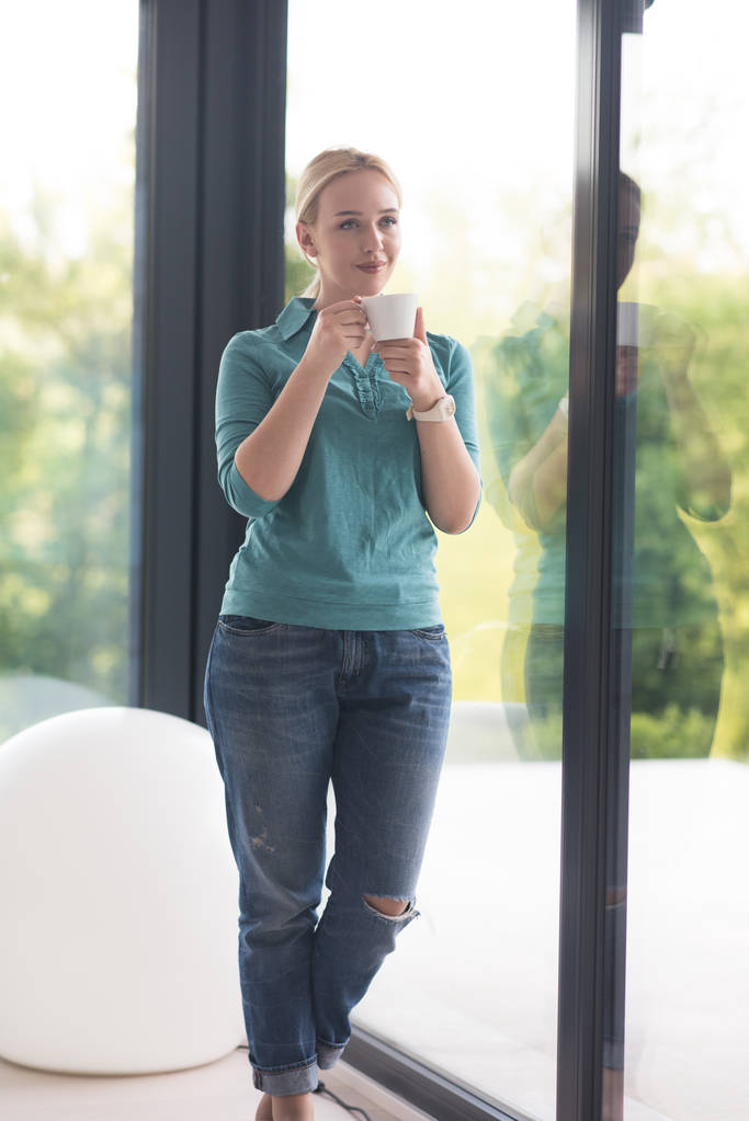 jovem mulher bebendo café da manhã pela janela
 - Foto, Imagem