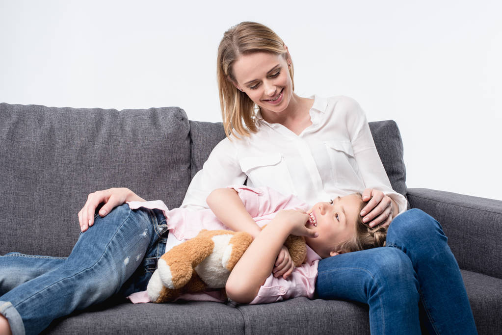 1 madre con hija pequeña sentada en el sofá
 - Foto, Imagen
