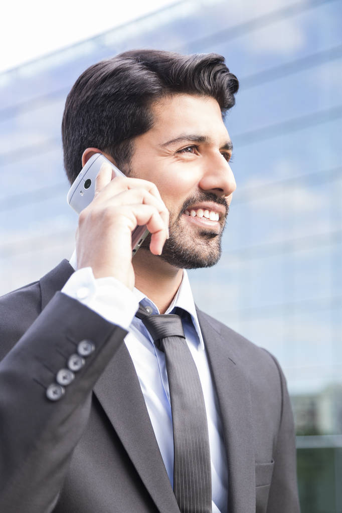 Hombre de negocios sonriente o trabajador en traje con teléfono cerca del edificio de oficinas
 - Foto, imagen