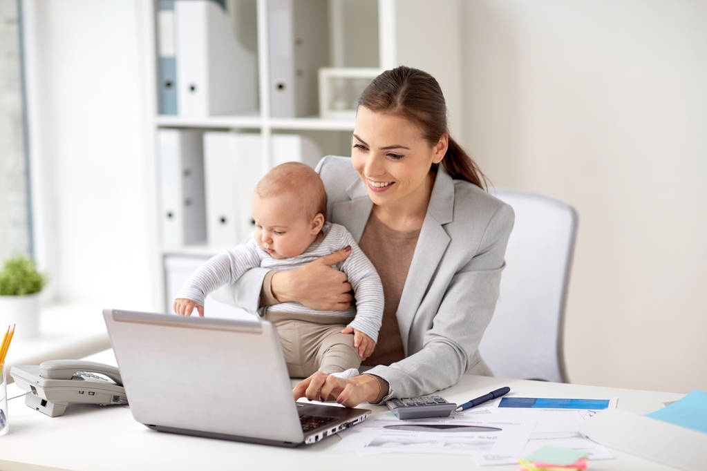 счастливая деловая женщина с ребенком и ноутбуком в офисе
 - Фото, изображение