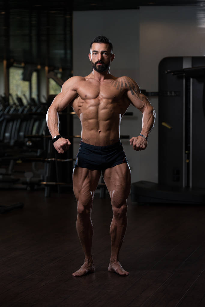 Hombre musculoso guapo flexionando músculos en el gimnasio
 - Foto, Imagen