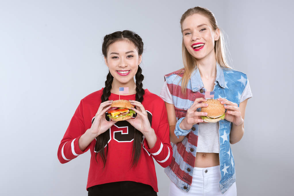 chicas sonrientes multiétnicas sosteniendo hamburguesas
 - Foto, Imagen