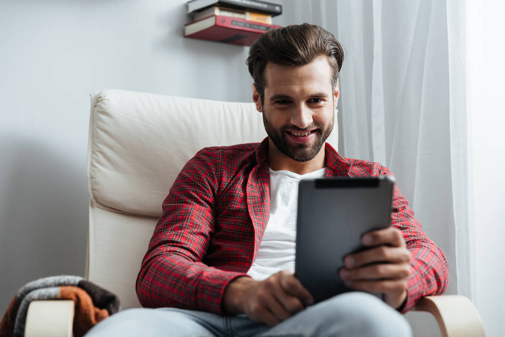 Šťastný mladý vousatý muž používající počítač tabletu. - Fotografie, Obrázek