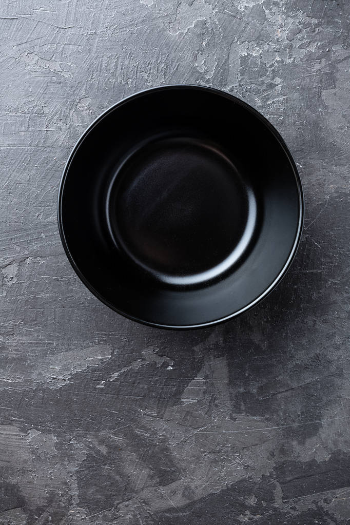 Prázdný černý talíř na tmavě šedém pozadí, pohled shora - Fotografie, Obrázek