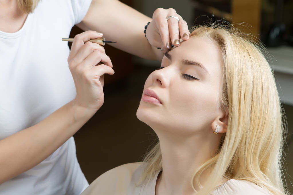 Συνθέτουν γυναίκα στη διαδικασία εργασίας εφαρμογή make up για ένα νεαρό bea - Φωτογραφία, εικόνα