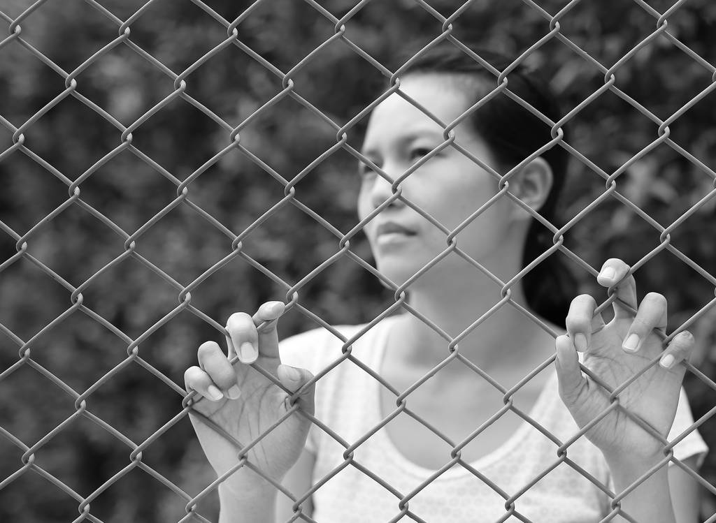 Mujer asiática al aire libre mirar hacia fuera con la mano sosteniendo la malla de acero, Enfoque en sus manos, tono blanco y negro
 - Foto, imagen