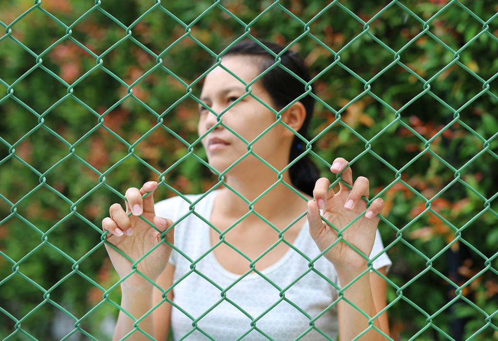 asiatische Frau im Freien schaut mit der Hand heraus, die das Stahlnetz hält, konzentriert sich auf ihre Hände - Foto, Bild