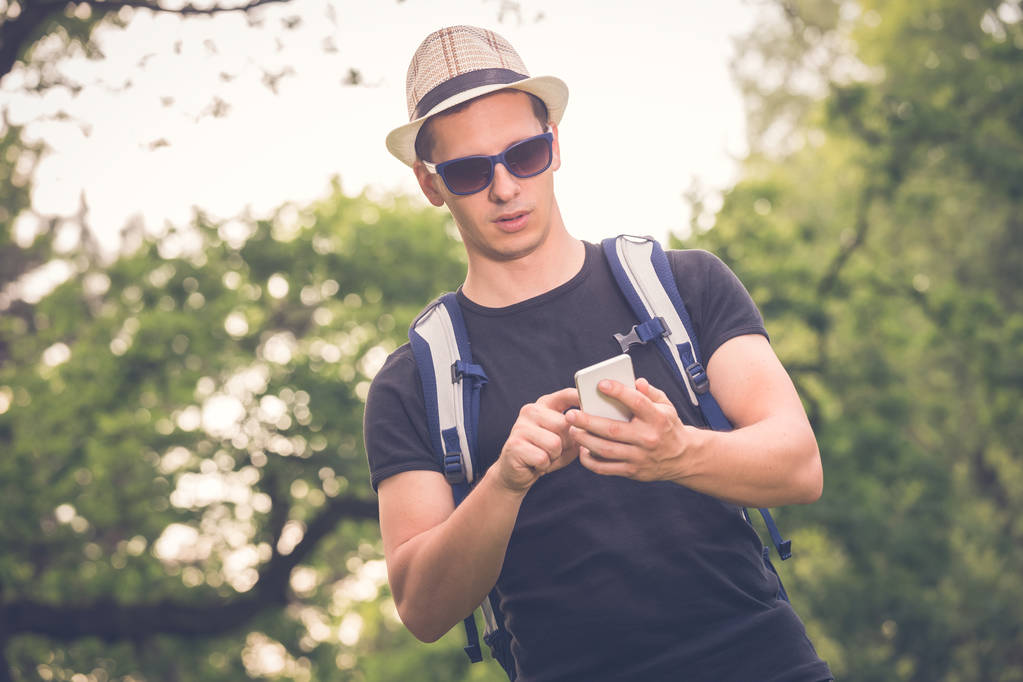 Portret facet młody turysta patrząc smartphone w przyrodzie - Zdjęcie, obraz