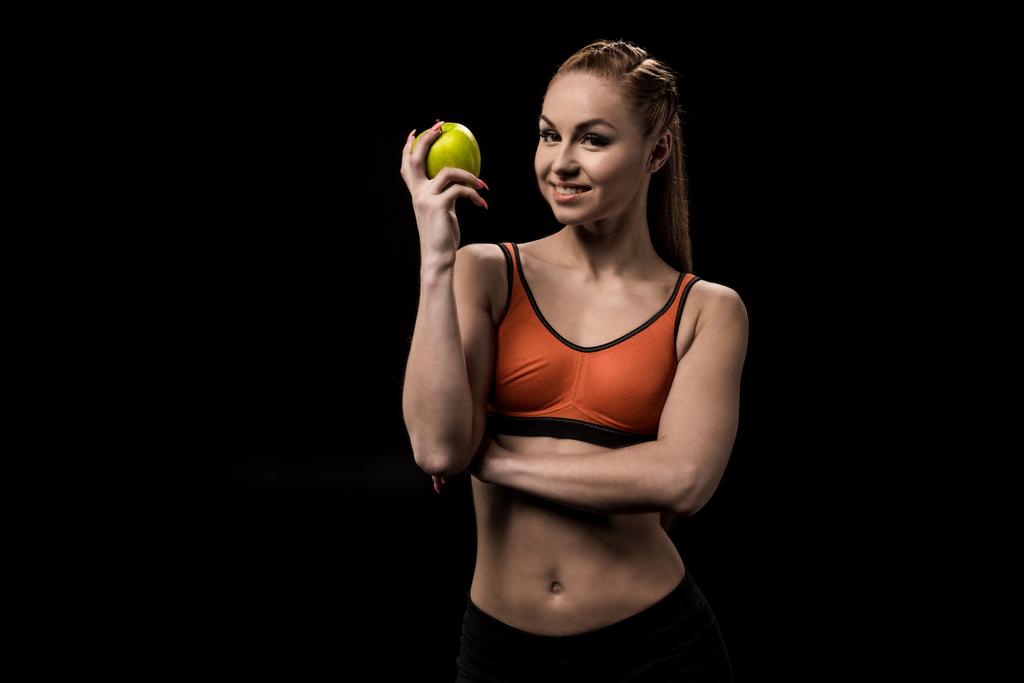 Улыбающаяся кавказская спортсменка держит яблоко
 - Фото, изображение