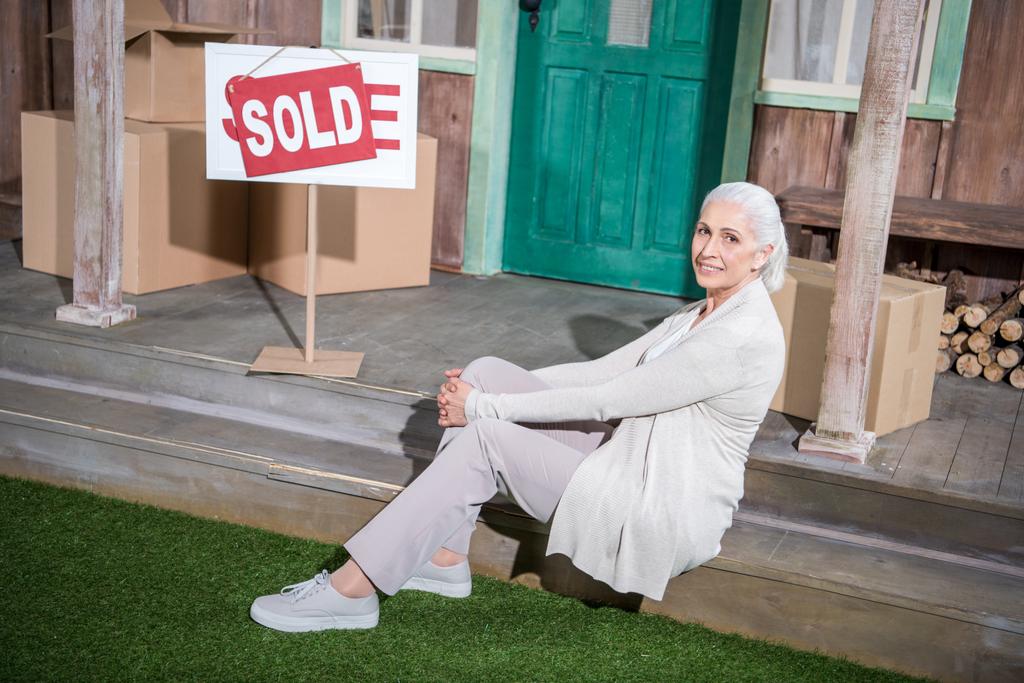 Старша жінка біля проданого будинку
  - Фото, зображення