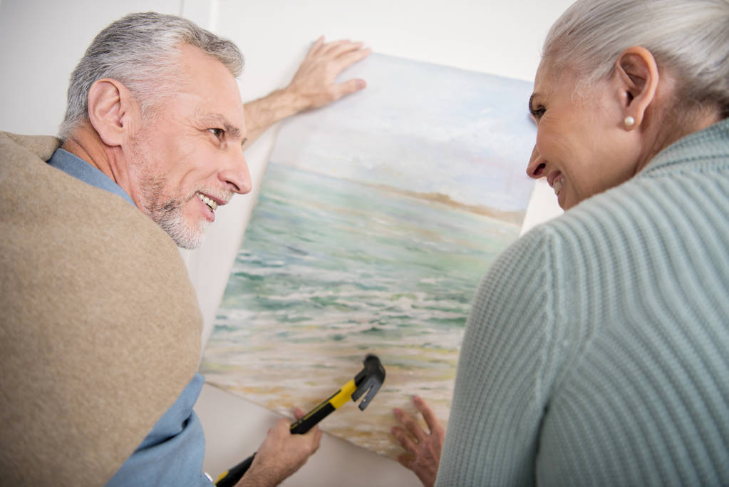 Seniorenpaar hängt Bild an Wand - Foto, Bild