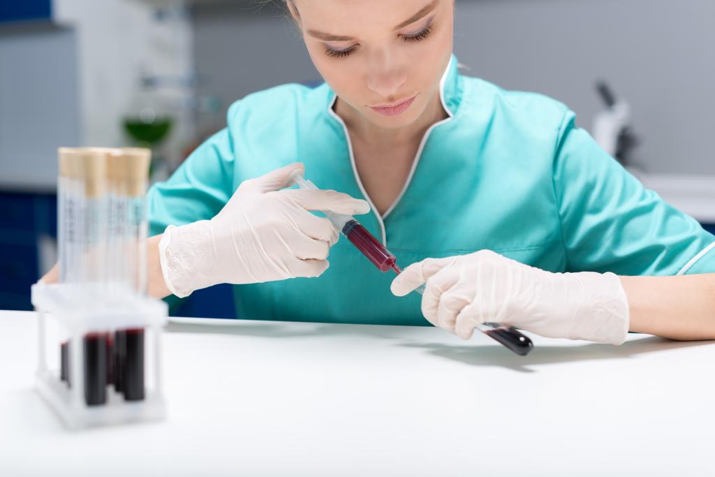Krankenschwester gießt Blutproben in Röhrchen - Foto, Bild