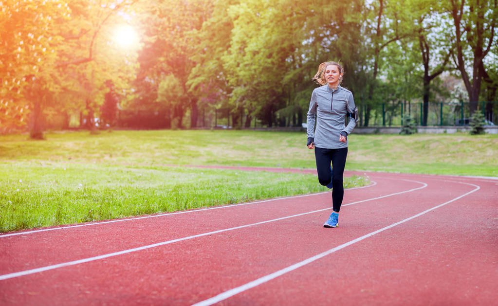 Sportliche Frau läuft mit Smartphone-App auf der Strecke, Fitness-Lifestyle - Foto, Bild