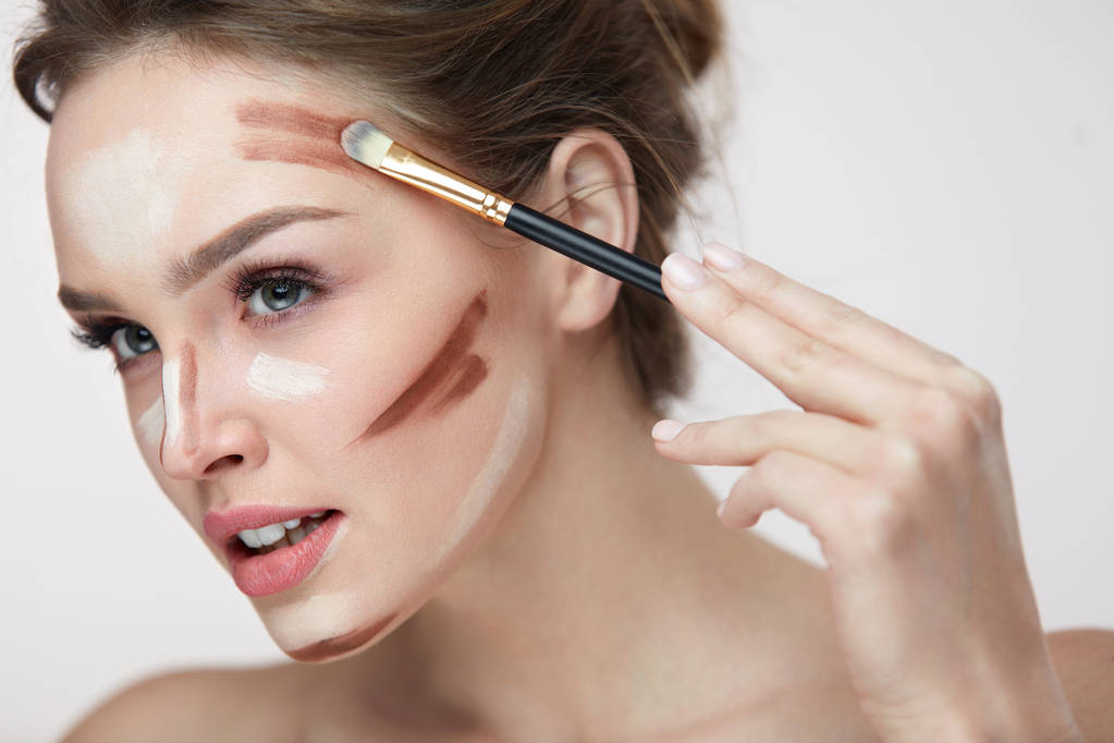 Maquiagem de beleza. Mulher bonita aplicando linhas de contorno no rosto
 - Foto, Imagem