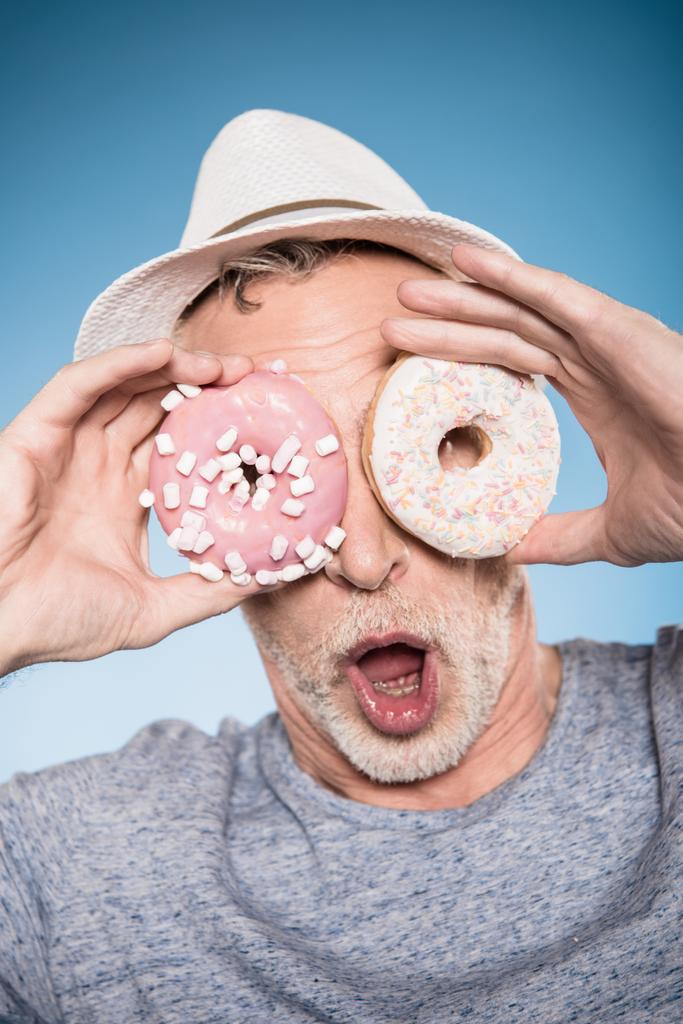 homem segurando donuts na frente dos olhos
 - Foto, Imagem