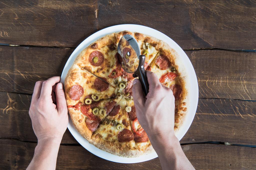 Persona cortando pizza
  - Foto, imagen