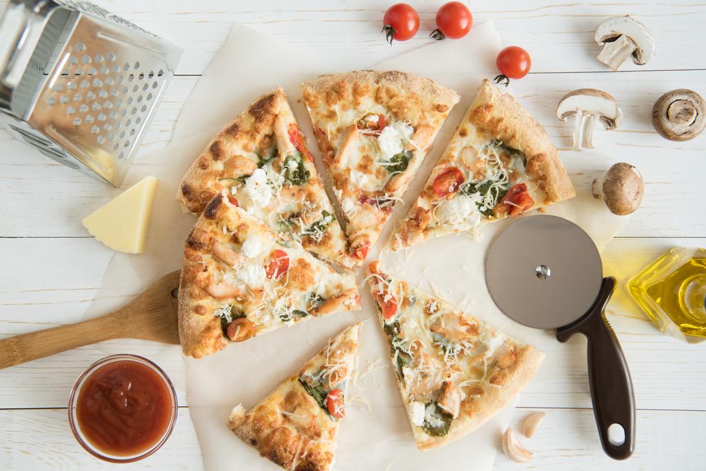 gesneden pizza met kaas en keukengerei - Foto, afbeelding