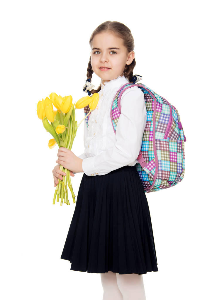 ein Schulmädchen mit einem Blumenstrauß und einem Rucksack auf dem Schoß - Foto, Bild