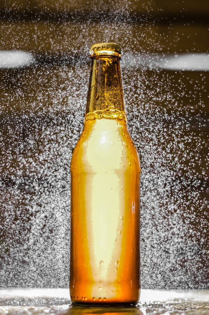 Primer plano de una sola botella de cerveza artesanal con burbujas de agua en el aire sobre fondo borroso
 - Foto, Imagen