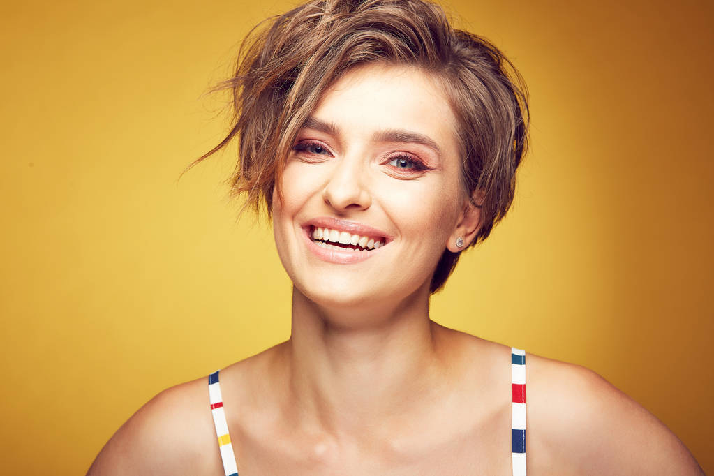 Zbliżenie portret seksowny szczęśliwy młody model piękne female krótkie rozczochrane włosy brązowe, i szczęśliwy uśmiechający się twarz, pozowanie Studio na żółtym tle - Zdjęcie, obraz