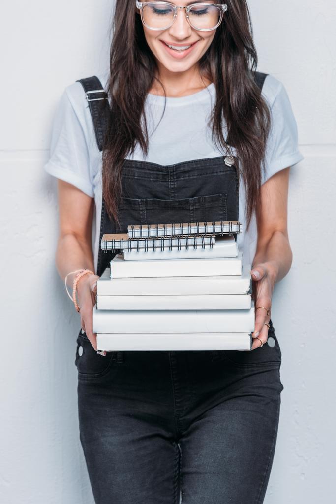 молода усміхнена біла жінка в окулярах тримає книги
  - Фото, зображення