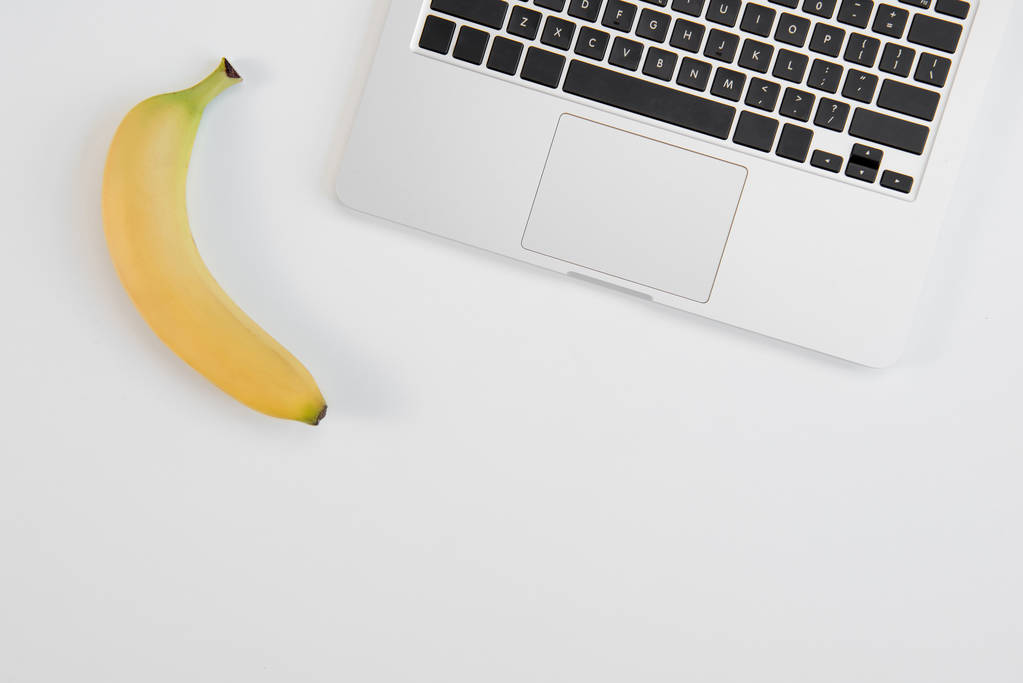 ノート パソコンと灰色の背景に分離された新鮮な熟したバナナの平面図 - 写真・画像