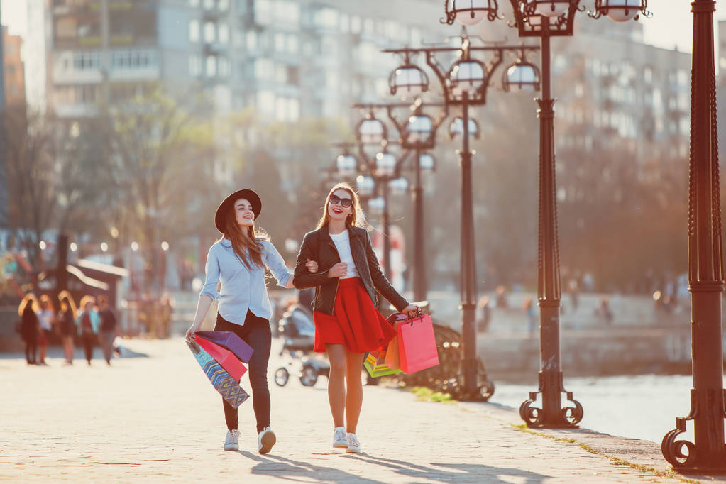 Дві дівчини ходять з покупками на міських вулицях
 - Фото, зображення