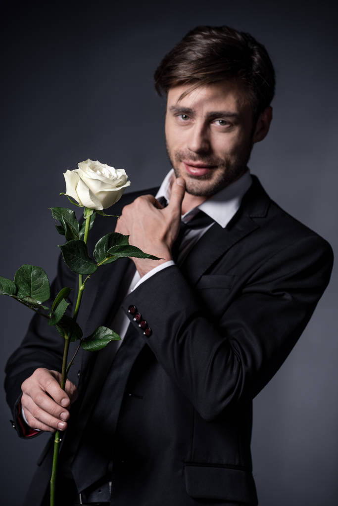 чоловік тримає троянду і дивиться на камеру
 - Фото, зображення
