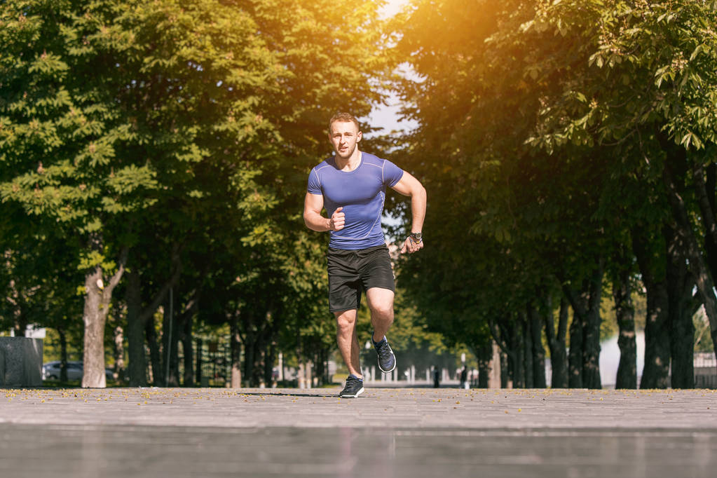 朝の公園で走っている男。健康的なライフ スタイルのコンセプト - 写真・画像