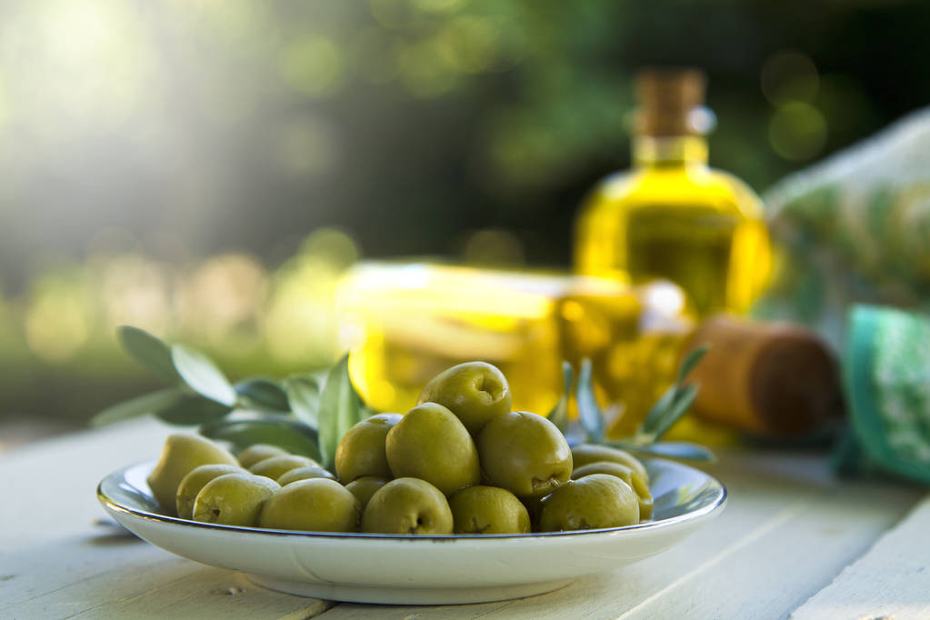 Placa de aceitunas y botellas de aceite de oliva sobre la mesa
 - Foto, Imagen