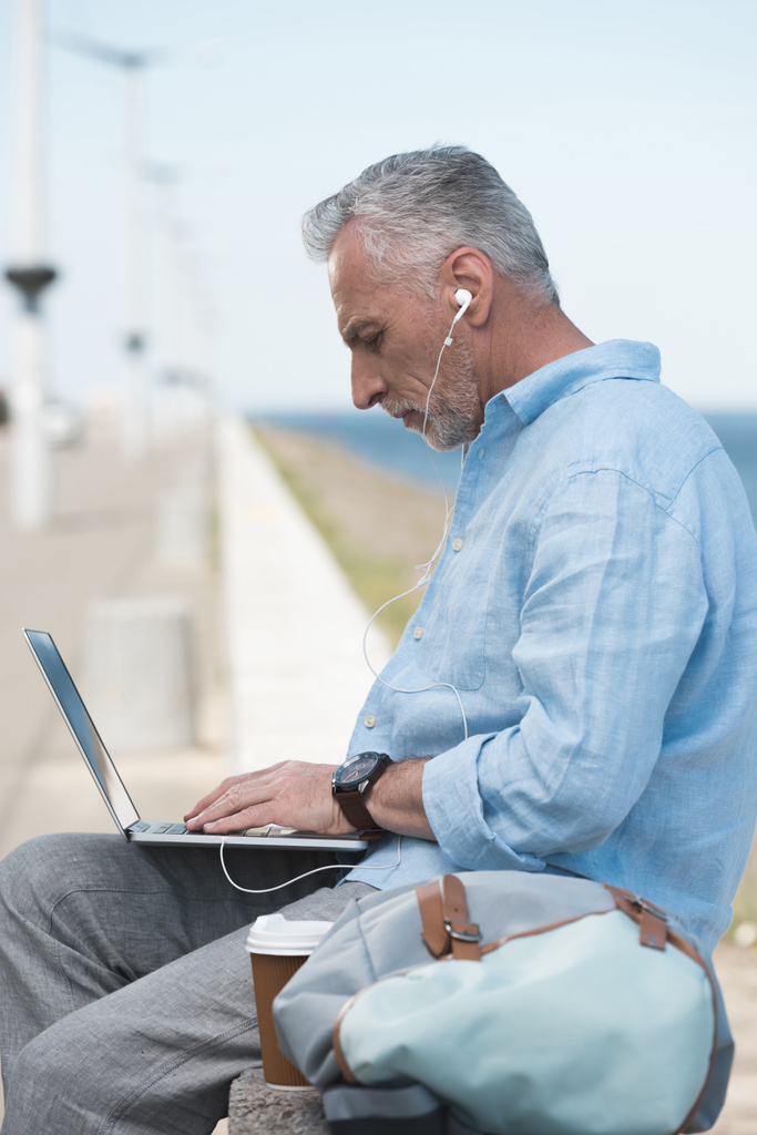літній чоловік друкує на ноутбуці на відкритому повітрі
 - Фото, зображення