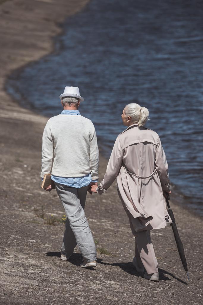 літня пара, що йде на березі річки
 - Фото, зображення