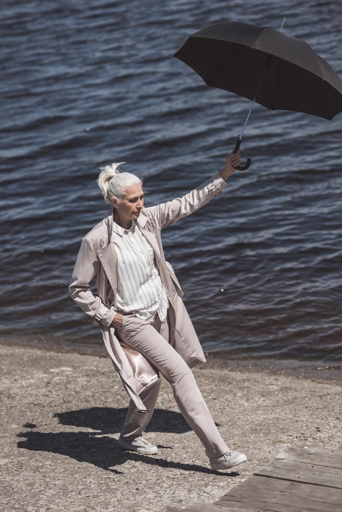 mulher andando com guarda-chuva na margem do rio
 - Foto, Imagem